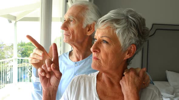 Senior couple looking through window in bedroom