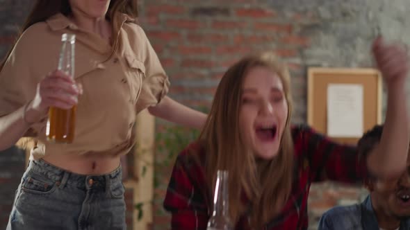 Excited Women Clink Bottles Celebrating Victory with Buddies