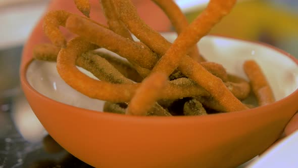 Rotating white clay bowl with tasty garnetted dough biscuits sprinkled with cinnamon, handheld close