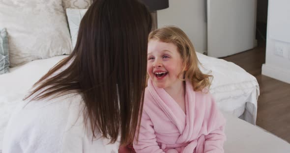 Caucasian mother and daughter having fun laughing in bedroom