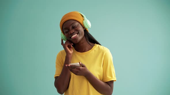 Pretty African woman wearing headphones dancing