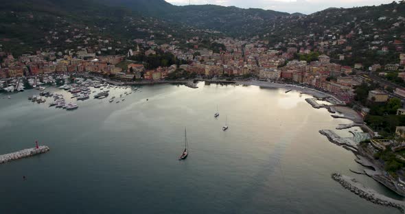 Golden hour aerial of tourist resort's colorful houses and packed marina, Italy
