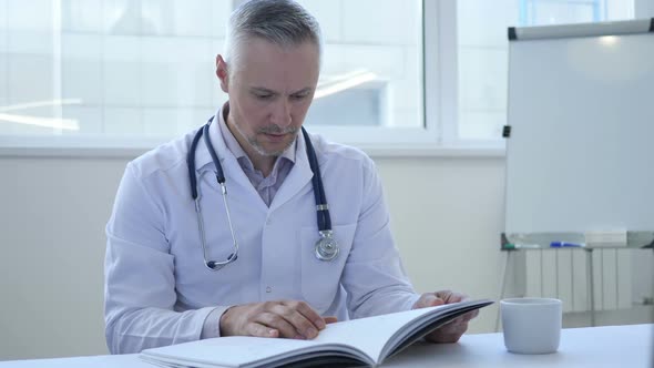 Doctor Reading Medical Book in Clinic