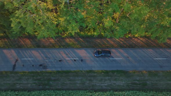 Aerial Footage of a Blue Car Driving Down a Country Road