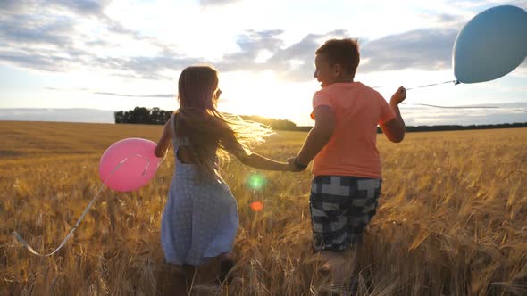 Couple of Little Kids with Balloons Running Through Wheat Field, Turning To Camera and Smiling