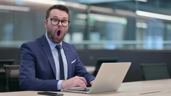 Middle Aged Businessman with Laptop Feeling Shocked