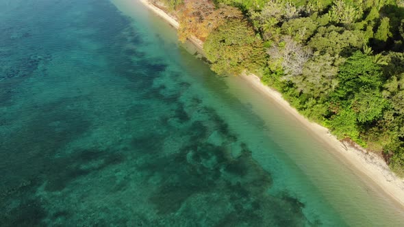 Aerial: flying over tropical Hatta island white sand beach Banda Islands Maluku