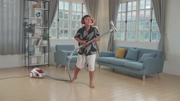 Cheerful Asian Boy Cleaning Up His Home And Singing