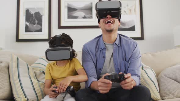 Happy biracial man and his son playing video games wearing vr headset