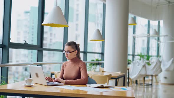 Beautiful business woman wearing light brown blouse working on her laptop