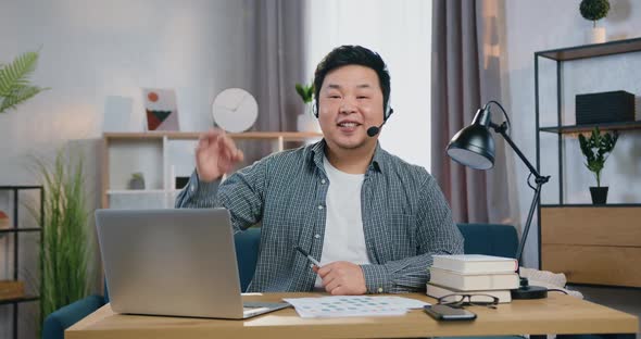 Man in Headphones Looking Into Camera in Home Office and Showing Gesture Ok