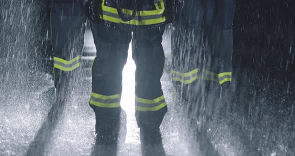 a Team of Professional Firefighters Stands in the Rain with Helmets and Fire Suit