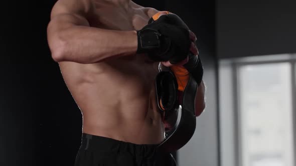 Young Shirtless Man Boxer Putting on Boxing Gloves