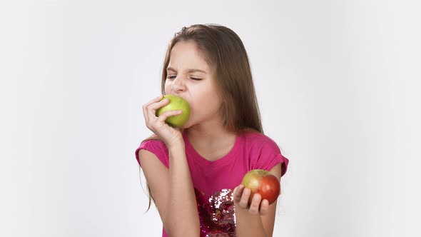 Girl with an Apple. Little Girl Eating an Apple Girl in a Pink Bright Dress on a White Background.