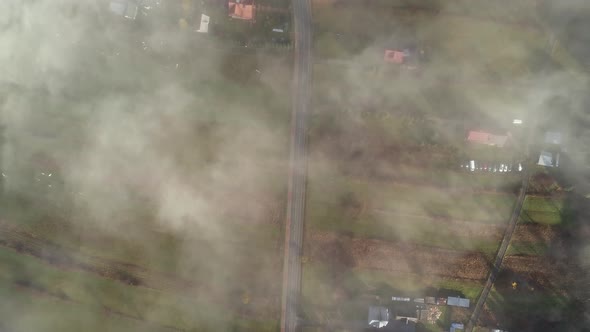 Rural road passing through Poland farmland covered in light mist, aerial