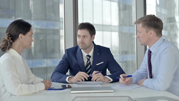 Middle Aged Businessman Having Discussion with His Assistants on Boardroom Table