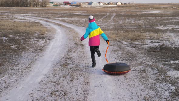 Young Girl Riding on Inflatable Snow Tube From a Hill