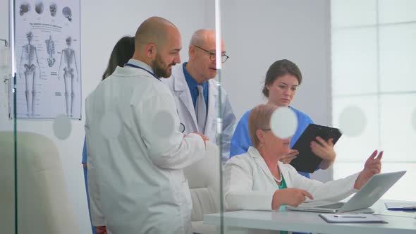 Senior Doctor Using Laptop Explaining to Colleagues Treatment of Patients