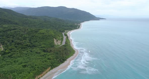 Backward flight with drone overlooking the beautiful beach los patos in barahona, blue waters cloudy