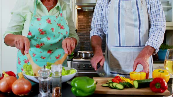 Senior couple preparing salad in kitchen 4k