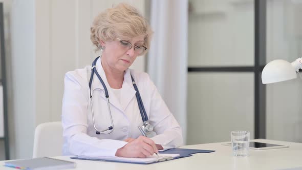Old Female Doctor Writing on Paper Medical Report