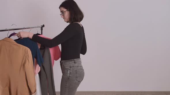 Beautiful Young Girl Standing at the Clothes Rack Picking Up Clothes Basic Wardrobe