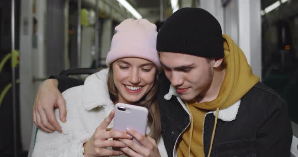 Crop View of Millennial Couple Looking at Smartphone Screen While Watching Video and Smiling