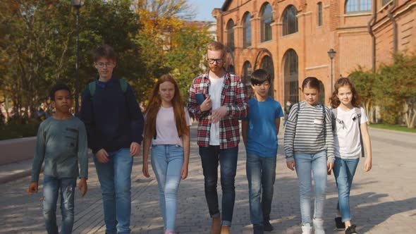 School Teacher and Group of Diverse Preteen Students Walking Outdoors