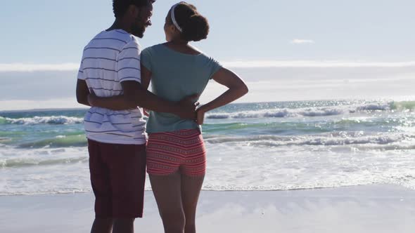 African american couple smiling and embracing on the beach