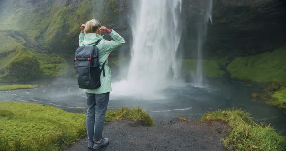 Woman with Backpack in Front of Epic Seljalandsfoss Waterfall Iceland