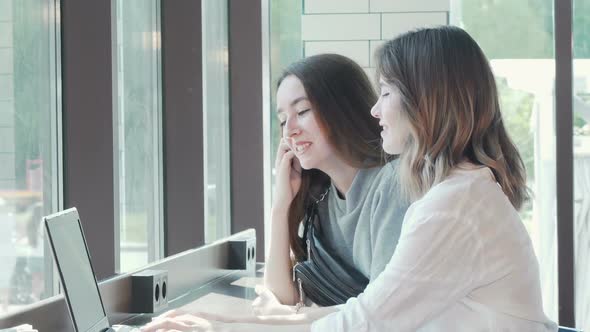 Two Young Women Studying Together at Campus Cafe Using Laptop