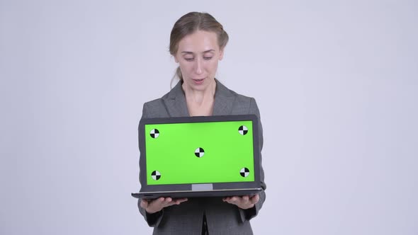 Happy Young Blonde Businesswoman Showing Laptop and Looking Surprised