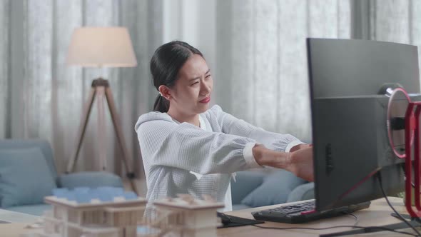 Asian Woman Engineer With The House Model Stretching After Working On A Desktop At Home