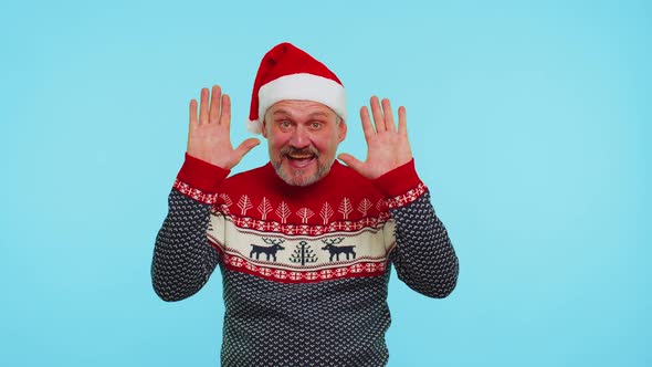 Positive Man in Christmas Sweater with Deers Waves Hand Palm in Hello Gesture Welcomes Someone