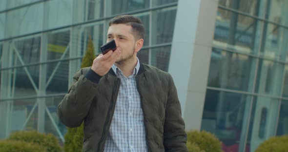 Man Using a Smartphone Voice Recording Function Online Walking on a City Street, Talking To Mobile