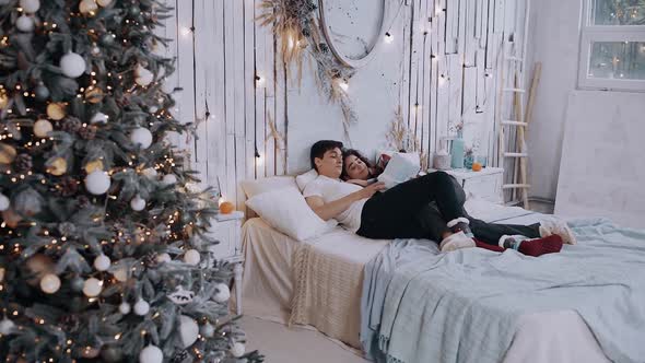 Young Romantic Couple Lying on the Bed with a Gift in Hand.