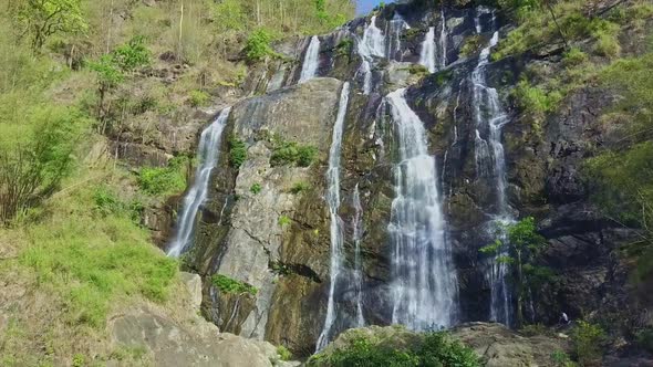 High Waterfall Cascade Runs Down Among Rocks in Highland
