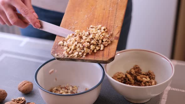 Process of Making Dough For Cake  Woman Pouring Chopped Crushed Walnuts Into Ceramic Bowl