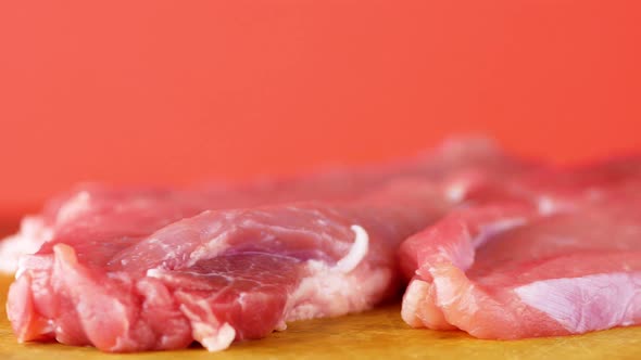 Close-up of pieces of raw red fatty pork meat rotate on a bright orange background. Meat products co