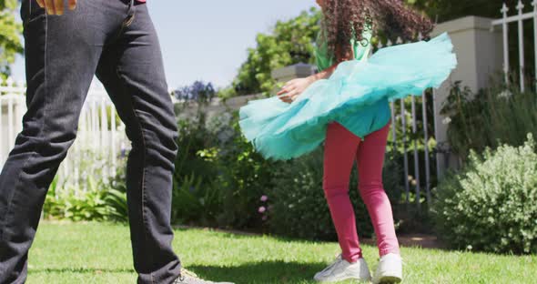 Happy biracial father and daughter dancing in garden together