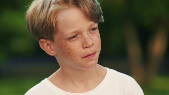 A happy boy with freckles is looking to the camera standing