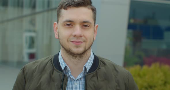 Close-up Portrait of Young Handsome Man Standing Outdoors Alone Smiling Looking at Camera. Beautiful