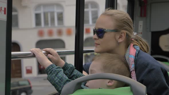 Mother and son looking at city from double-decker bus