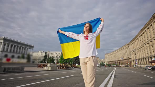 Patriotic Woman in Embroidery Lifts Bright Ukrainian Flag