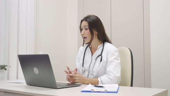 Smiling Female Medical Assistant Video Calling Distant Patient on Laptop