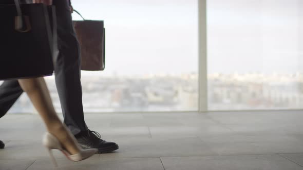 Legs of Businesspeople Walking before Panoramic Window
