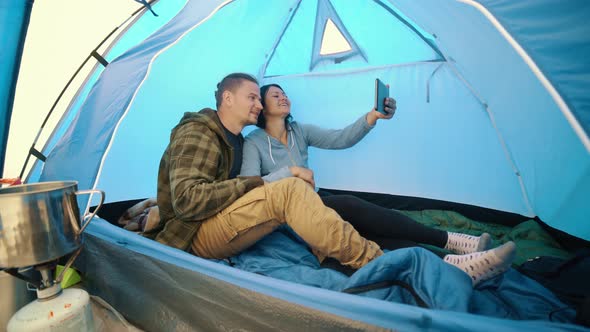 Young Couple Talking During Online Video Call on Tablet in Camping Tent