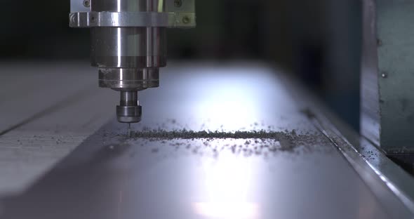 Milling Machine Cuts a Part From a Sheet of Plastic Shavings Fly