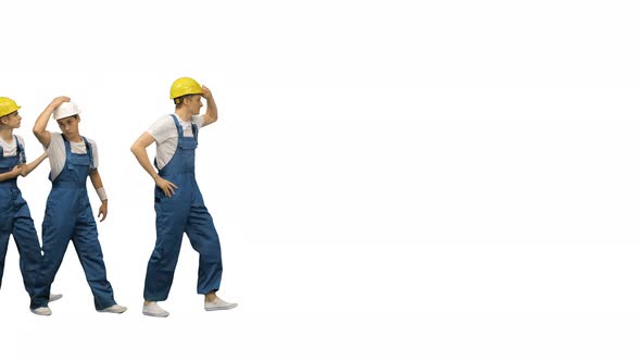 Three Young Construction Workers Doing a Funny Row Dance Touching Their Hardhats and Pointing