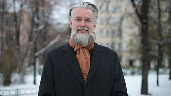 gray-haired bearded stylish man in coat outdoors on winter morning